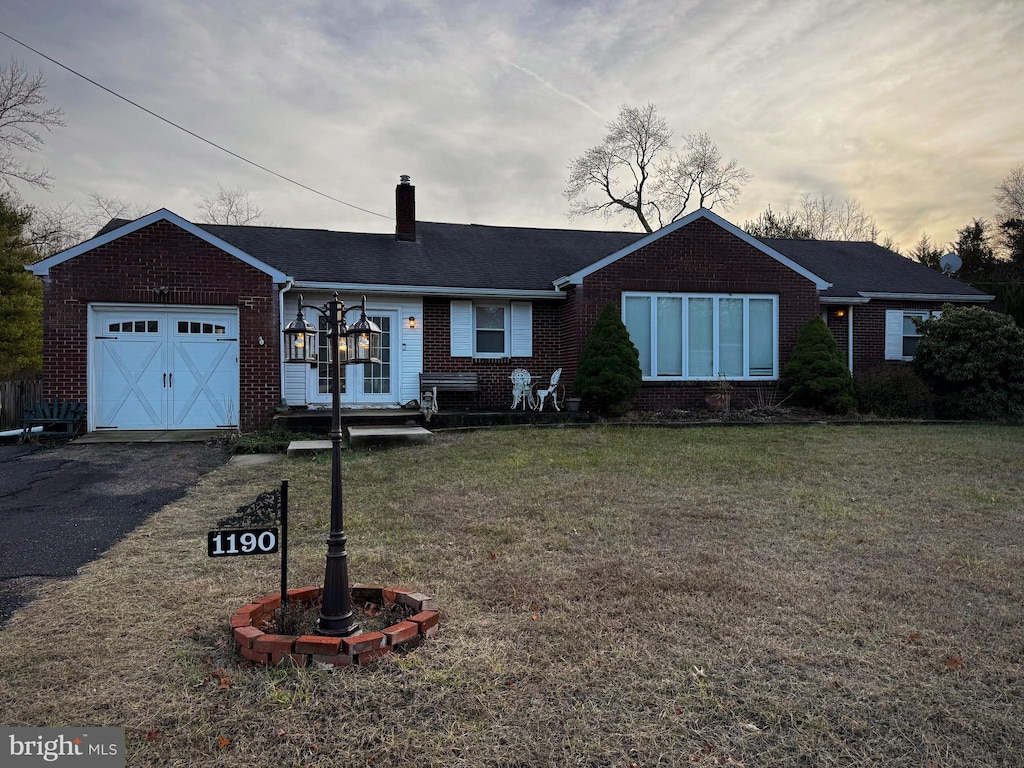 single story home featuring a garage and a yard