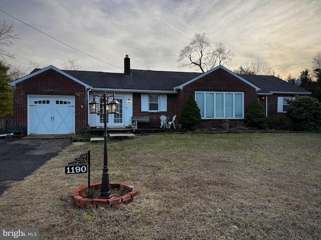 single story home featuring a garage and a yard