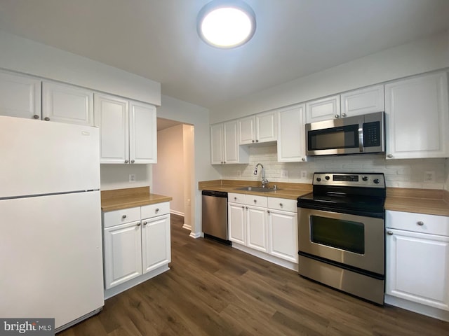 kitchen with butcher block counters, white cabinetry, sink, and stainless steel appliances