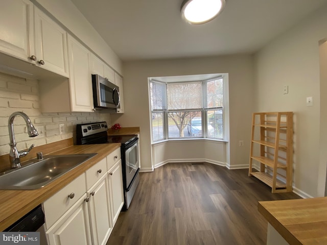 kitchen featuring wood counters, stainless steel appliances, white cabinetry, and sink