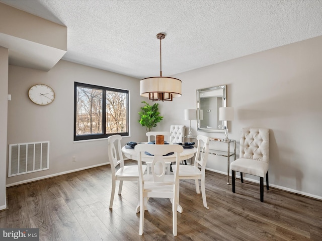 dining area with a textured ceiling and dark hardwood / wood-style floors