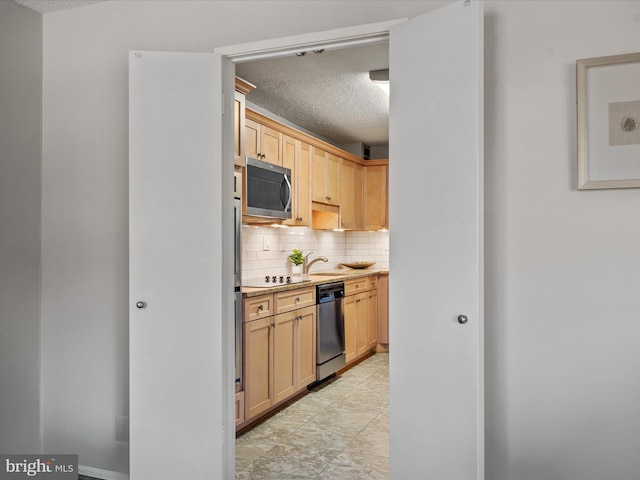 kitchen with decorative backsplash, a textured ceiling, light brown cabinetry, and appliances with stainless steel finishes