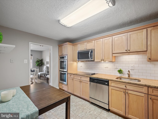 kitchen featuring light stone counters, a textured ceiling, sink, stainless steel appliances, and light brown cabinets