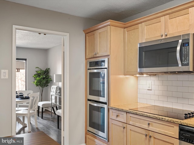 kitchen featuring stainless steel appliances, tasteful backsplash, wood-type flooring, light brown cabinetry, and light stone countertops