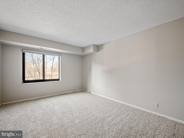 carpeted empty room featuring a textured ceiling