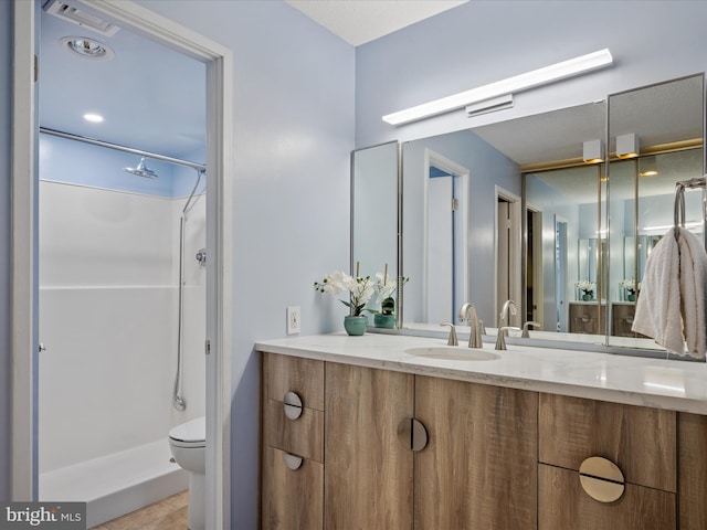 bathroom featuring vanity, walk in shower, and toilet