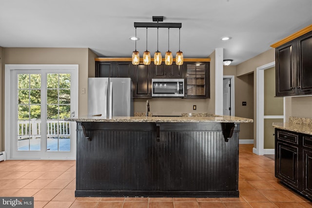 kitchen with a kitchen breakfast bar, light stone counters, stainless steel appliances, light tile patterned floors, and hanging light fixtures