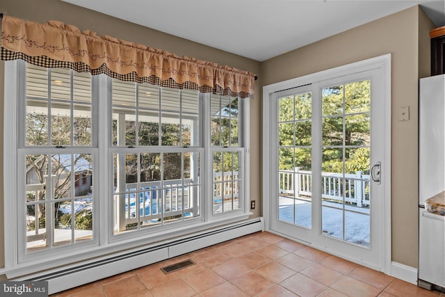 doorway to outside with light tile patterned floors, a baseboard radiator, and a wealth of natural light