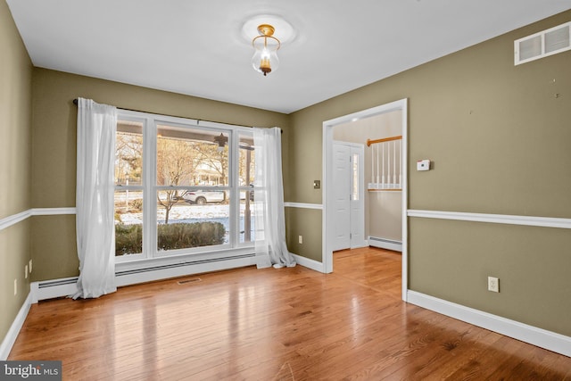 empty room with light hardwood / wood-style floors and a baseboard heating unit