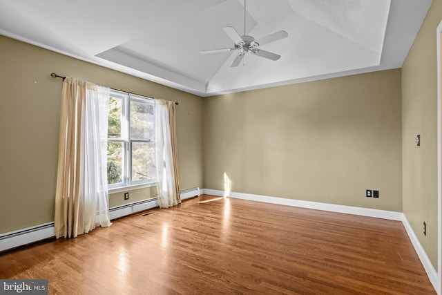 unfurnished room with a tray ceiling, ceiling fan, baseboard heating, and light wood-type flooring