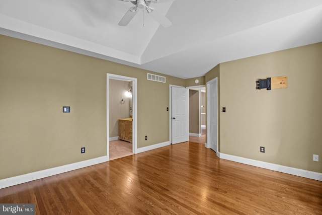 unfurnished bedroom featuring ceiling fan, wood-type flooring, connected bathroom, and vaulted ceiling