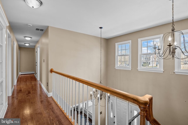 hall with dark wood-type flooring, an inviting chandelier, and a baseboard heating unit