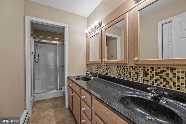 bathroom with backsplash, vanity, a shower with shower door, and baseboard heating