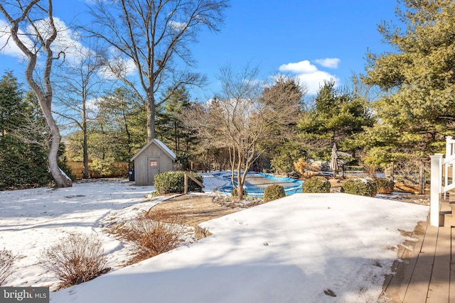 yard covered in snow featuring a pool and a storage unit