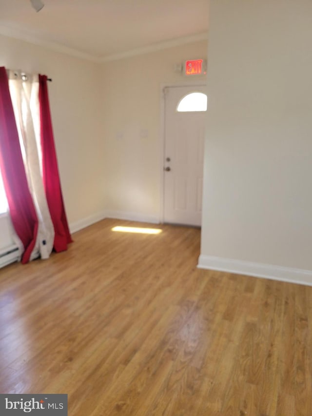 spare room with ornamental molding, baseboards, and wood finished floors