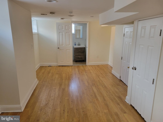 interior space featuring light wood finished floors, baseboards, and a sink