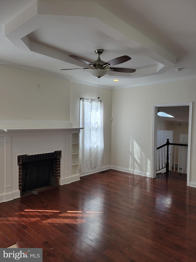 unfurnished living room featuring dark wood-style floors, a fireplace, baseboards, and a raised ceiling