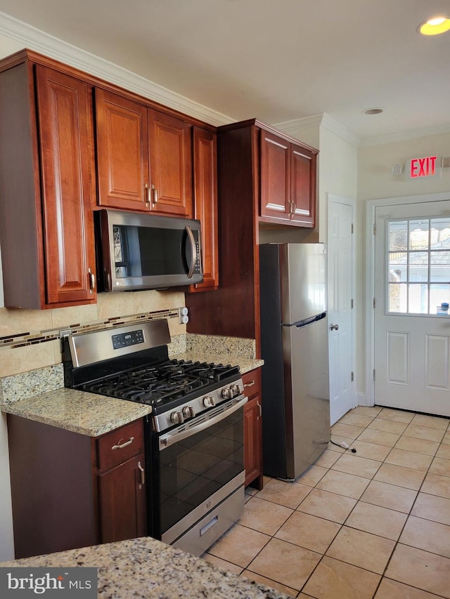 kitchen with light tile patterned flooring, appliances with stainless steel finishes, backsplash, light stone countertops, and crown molding