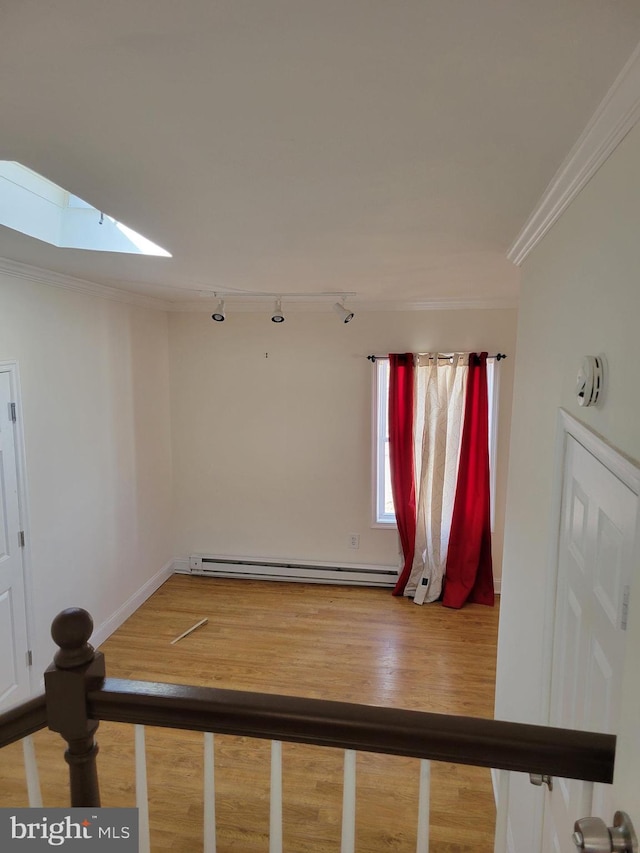 spare room featuring a skylight, baseboards, ornamental molding, wood finished floors, and baseboard heating