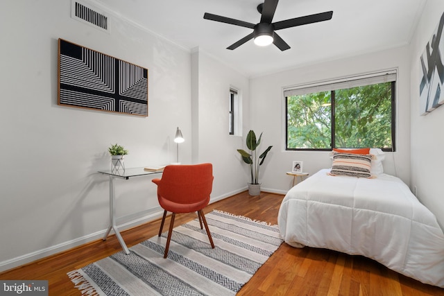 bedroom with hardwood / wood-style floors, ornamental molding, and ceiling fan