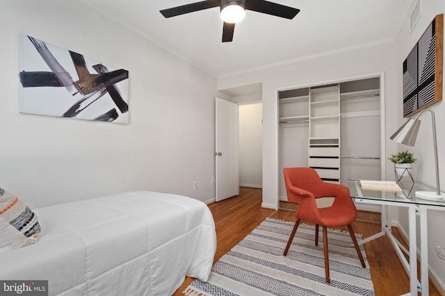 bedroom with hardwood / wood-style flooring, crown molding, ceiling fan, and a closet