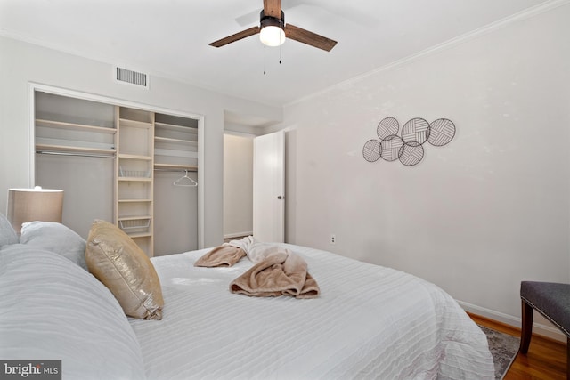 bedroom featuring hardwood / wood-style flooring, ceiling fan, crown molding, and a closet