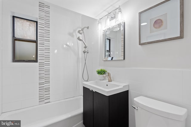 full bathroom featuring vanity, tiled shower / bath combo, tile walls, and toilet