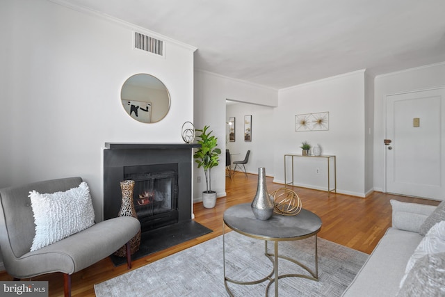 living room with ornamental molding and light hardwood / wood-style floors