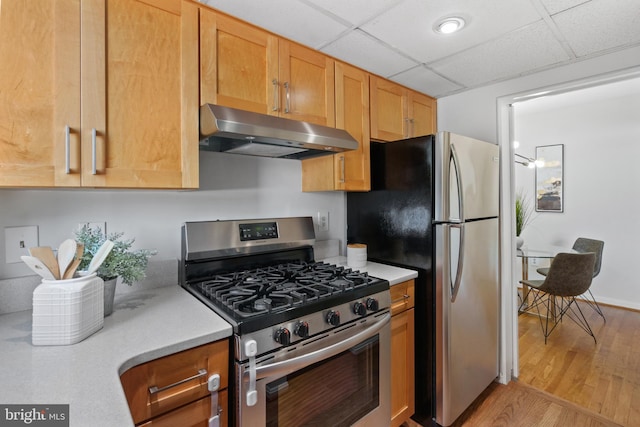 kitchen featuring stainless steel appliances, a drop ceiling, and light hardwood / wood-style flooring