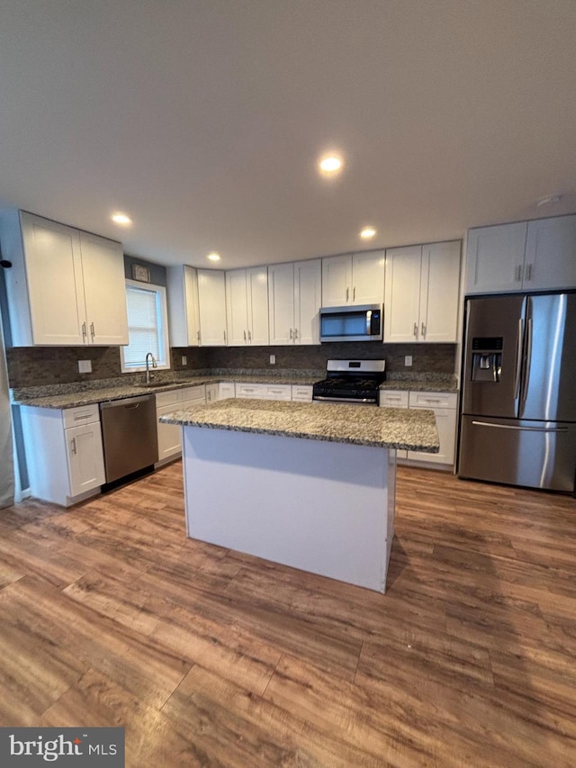 kitchen with wood-type flooring, appliances with stainless steel finishes, a center island, and white cabinets