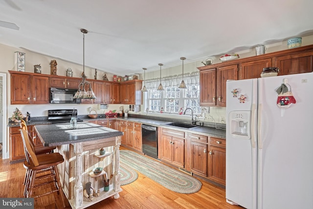 kitchen featuring pendant lighting, black appliances, a kitchen breakfast bar, sink, and a kitchen island