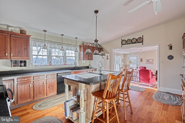 kitchen with ceiling fan, a center island with sink, light hardwood / wood-style flooring, black dishwasher, and a breakfast bar area