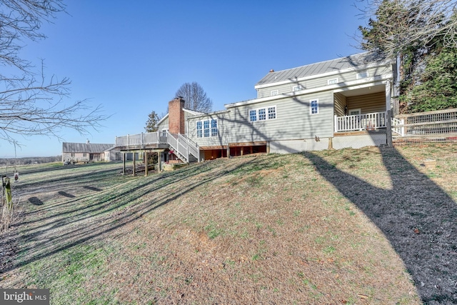 rear view of property featuring a wooden deck and a yard