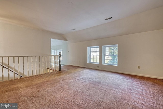 spare room featuring carpet flooring and vaulted ceiling