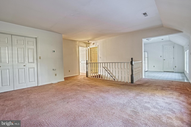 carpeted spare room featuring vaulted ceiling