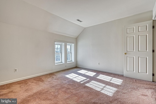 carpeted spare room with vaulted ceiling