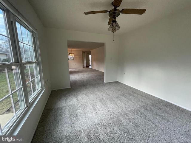 spare room featuring plenty of natural light, carpet floors, and ceiling fan with notable chandelier