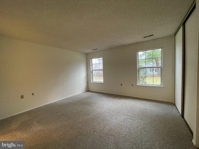 carpeted spare room with a textured ceiling