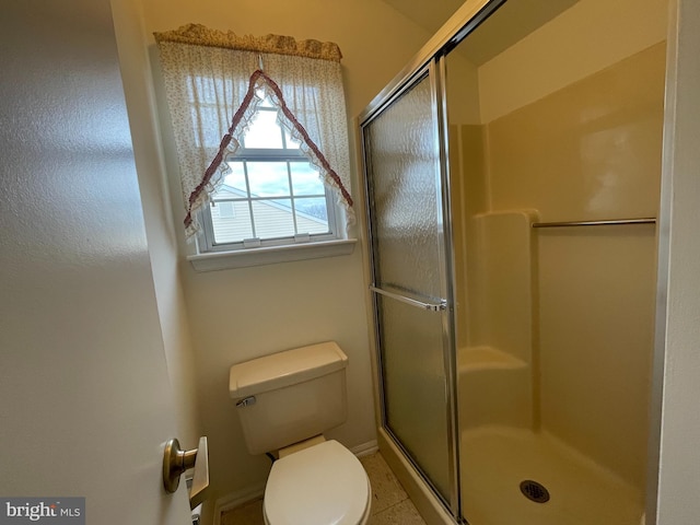 bathroom featuring tile patterned flooring, a shower with shower door, and toilet