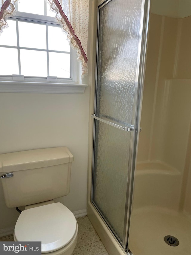 bathroom with tile patterned flooring, toilet, and a shower with shower door