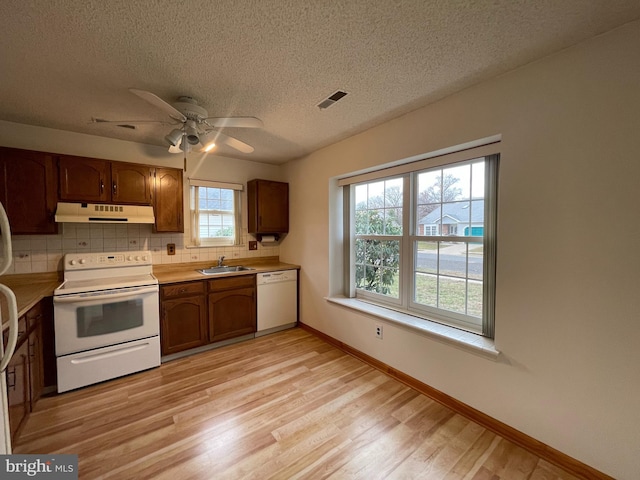 kitchen featuring white appliances, sink, light hardwood / wood-style flooring, ceiling fan, and tasteful backsplash