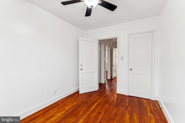 unfurnished bedroom with ceiling fan and dark wood-type flooring