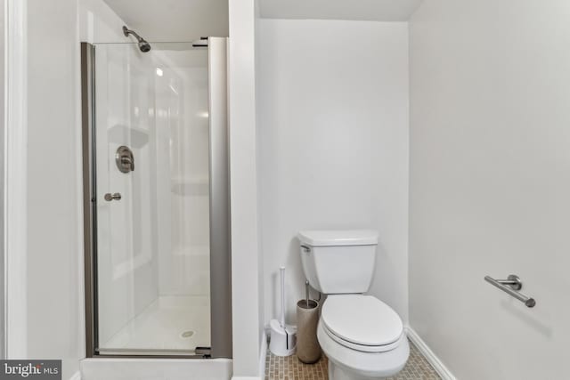 bathroom featuring tile patterned flooring, toilet, and a shower with shower door