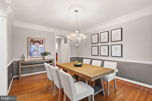 dining area featuring a notable chandelier, wood-type flooring, and ornamental molding