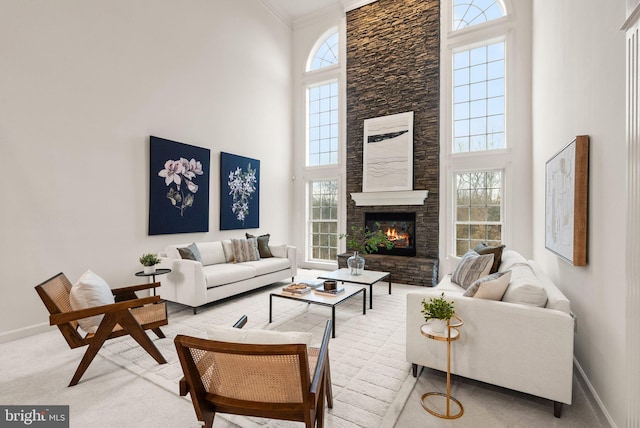 carpeted living room featuring ornamental molding, plenty of natural light, and a stone fireplace