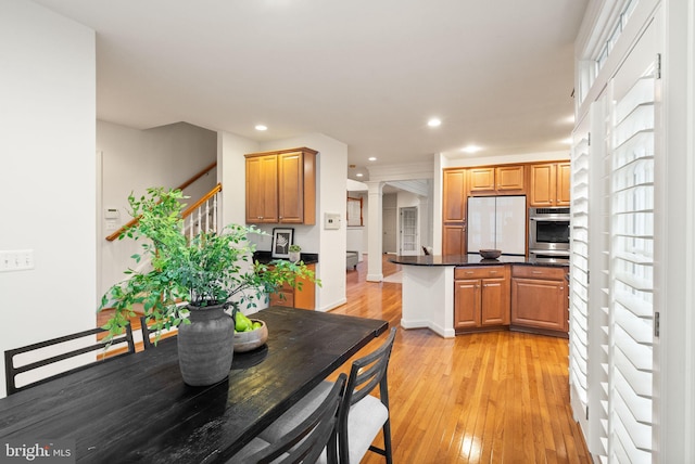 kitchen featuring white refrigerator, kitchen peninsula, light hardwood / wood-style floors, and ornate columns