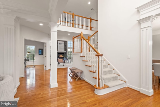 stairway with hardwood / wood-style flooring, ornamental molding, a towering ceiling, and ornate columns