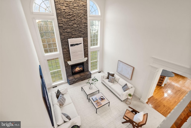 living room with a stone fireplace and a towering ceiling