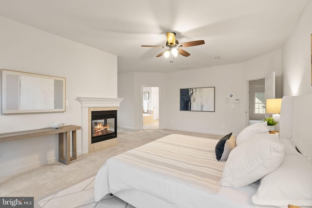 bedroom featuring ceiling fan, light colored carpet, ensuite bath, and a tile fireplace