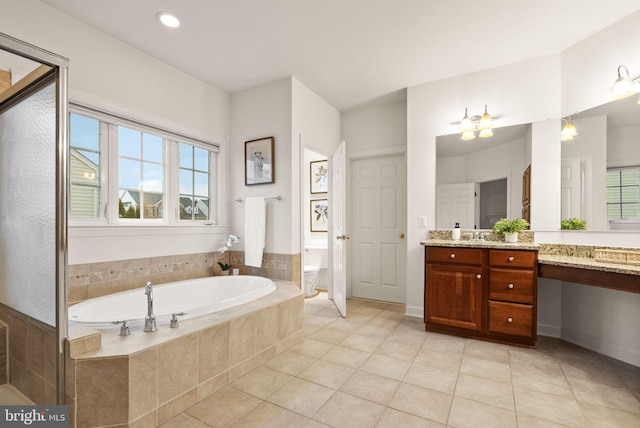 bathroom with vanity, tiled tub, tile patterned flooring, and toilet